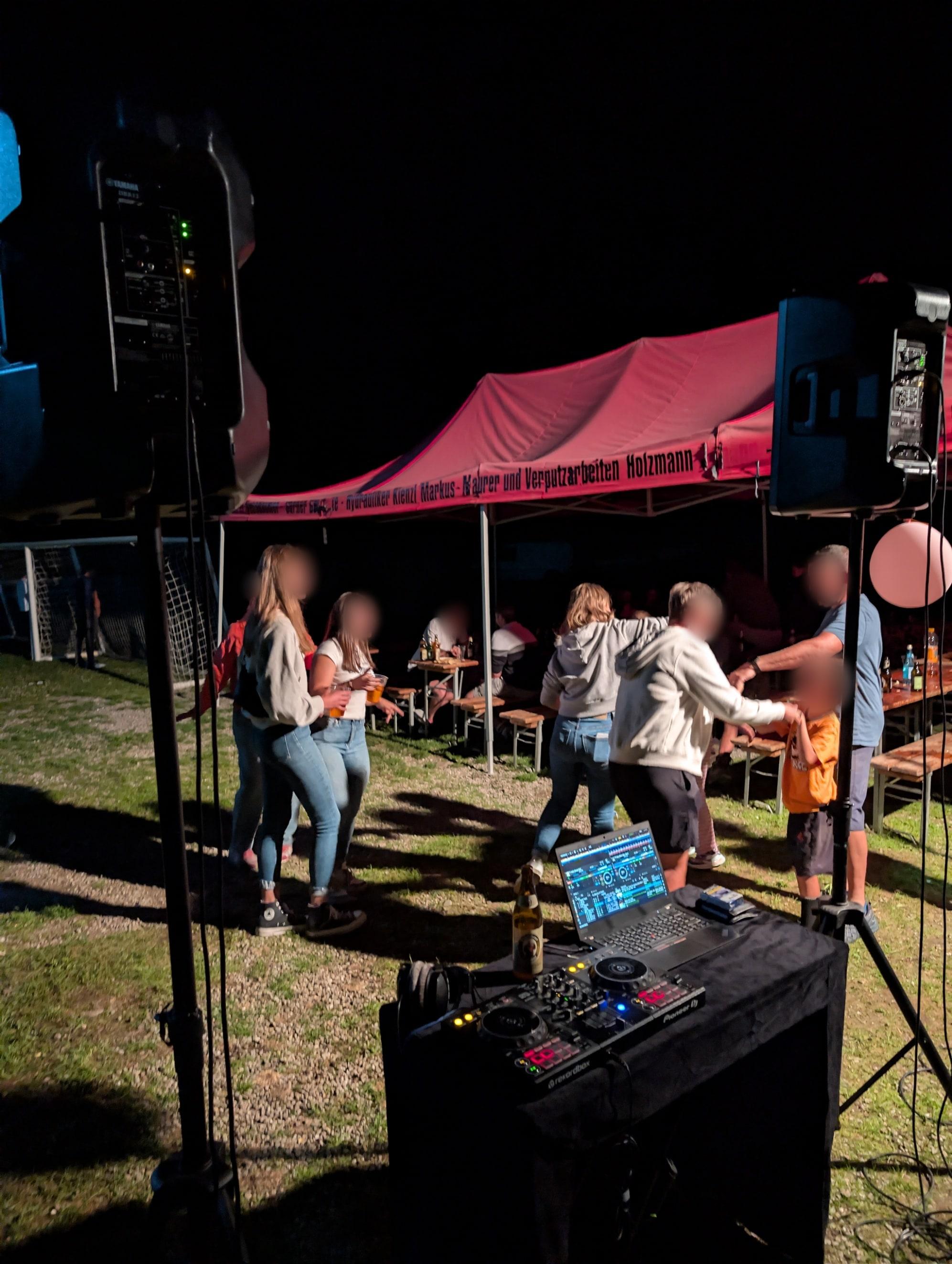 Tanzende Gäste vor dem DJ-Pult bei einem Open-Air-Fest